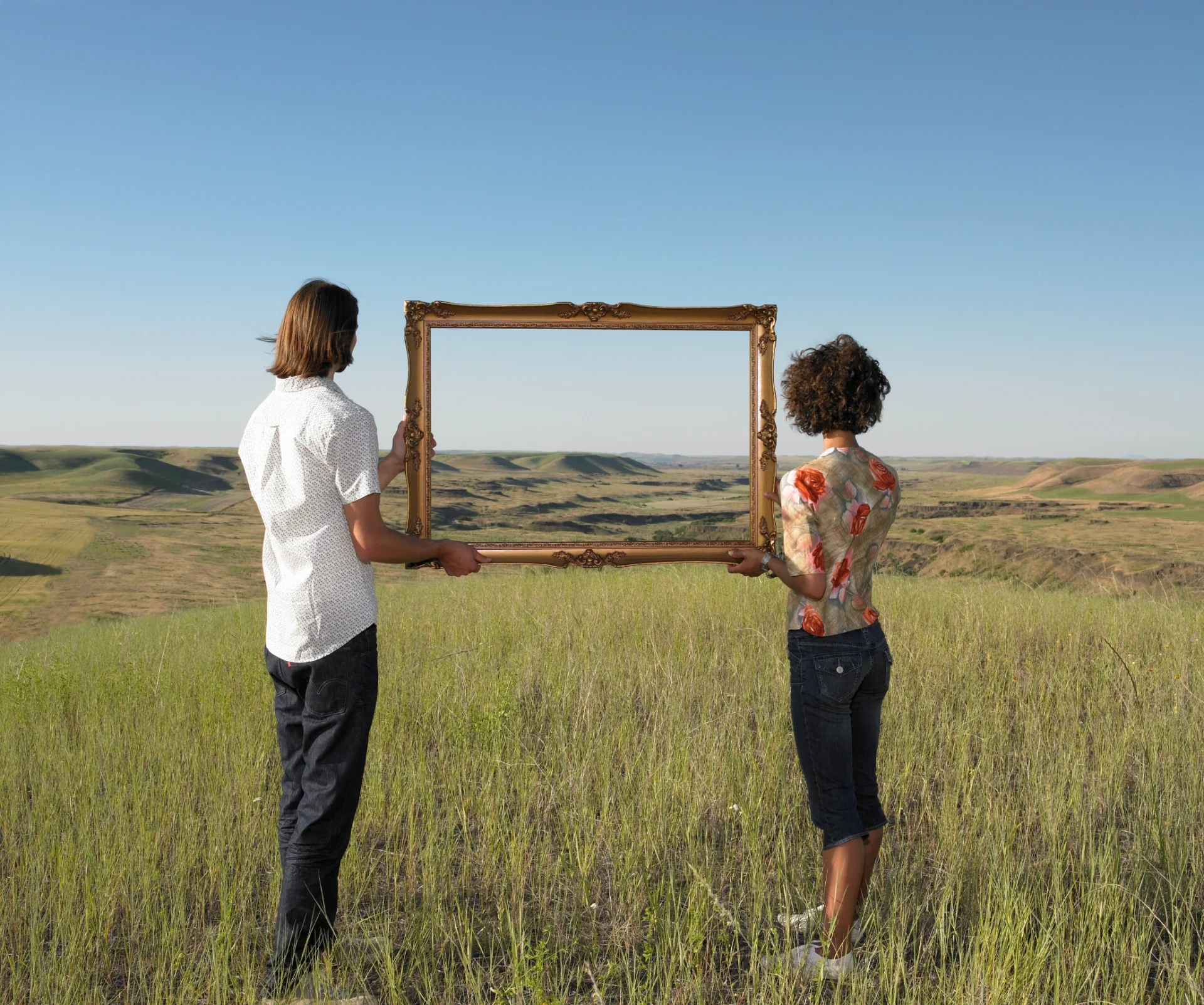 Two individuals holding empty frame outdoors